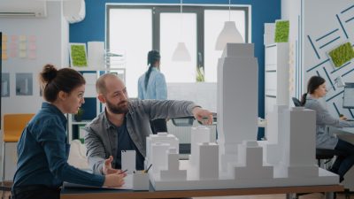 colleagues-doing-teamwork-designing-blueprints-plan-after-analyzing-building-model-team-people-using-maquette-create-architectural-construction-urban-development-project