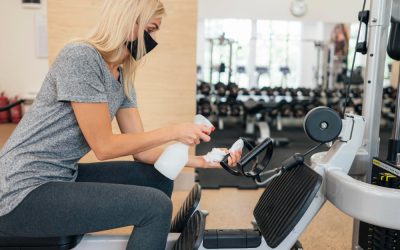 side-view-woman-spraying-disinfectant-gym-equipment